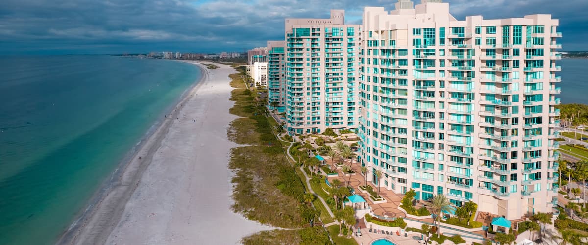 A coastal resort with a beach, a swimming pool, and high-rise buildings.