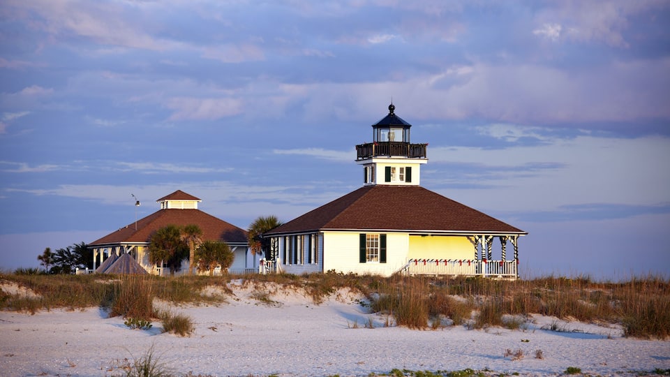 A coastal building with a lighthouse on a sandy beach.