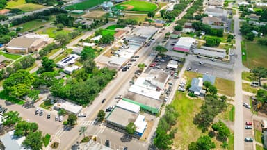 An aerial view of a town with a prominent tower, green fields, and a mix of commercial and residential buildings.