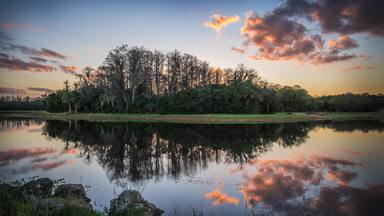 HWTX01 Clouds flank the sky and waters of Harns Marsh in Lehigh Acres, Florida at sunset.