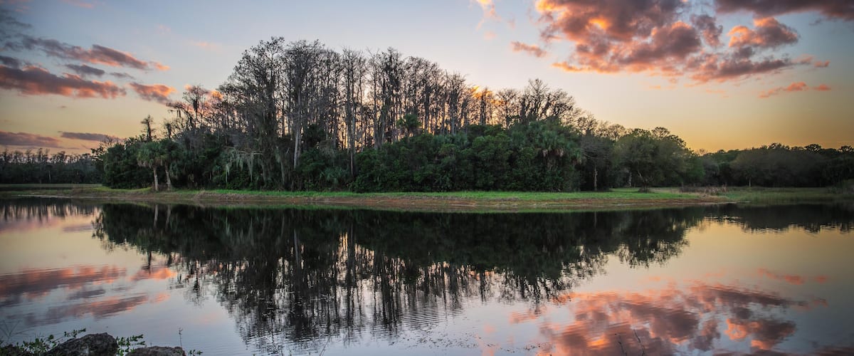 HWTX01 Clouds flank the sky and waters of Harns Marsh in Lehigh Acres, Florida at sunset.