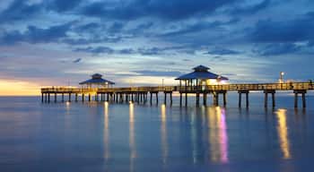 Un muelle con dos pabellones que se adentra en aguas tranquilas al atardecer.