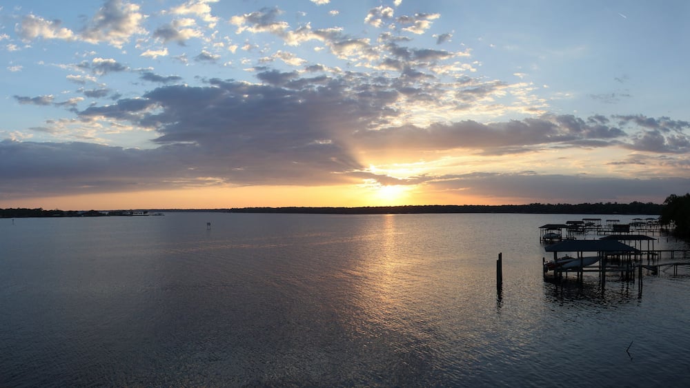 Ein Sonnenuntergang über einem ruhigen See mit einem Steg und Booten.