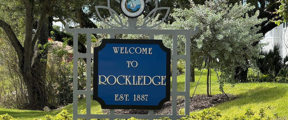 A welcome sign to Rockledge with a date of establishment, surrounded by greenery and trees.