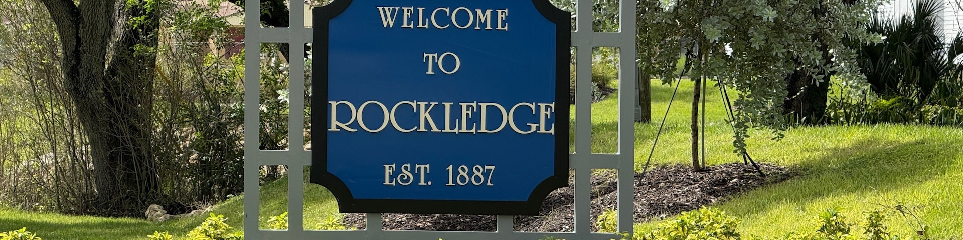 A welcome sign to Rockledge with a date of establishment, surrounded by greenery and trees.