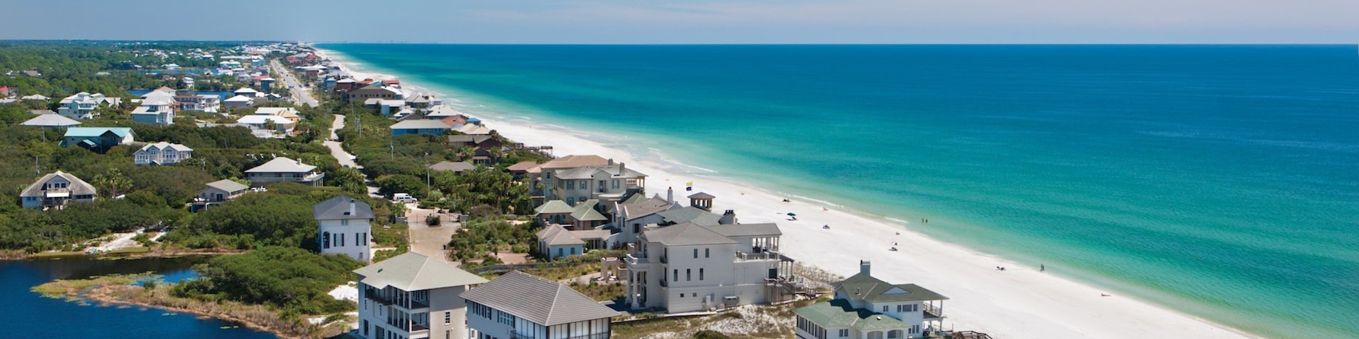 A coastal residential area with beachfront properties, a sandy beach, and a clear blue ocean.