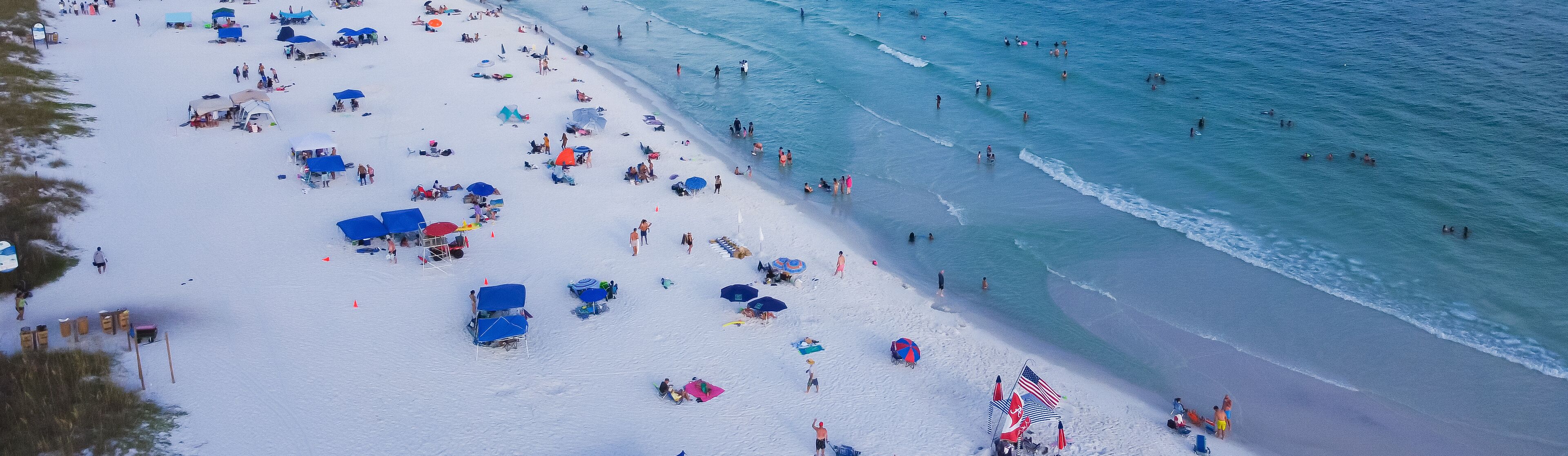 Panorama diverse crowed people swimming, relaxing on sugar white sandy shoreline, turquoise water, South Walton beach, Destin, Florida, USA, colorful tents, canopy, lounge chairs