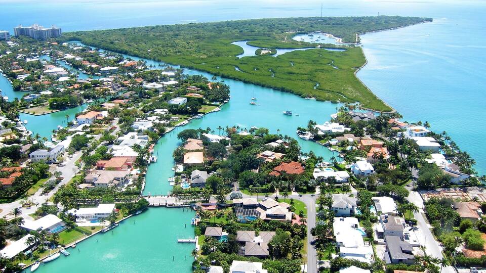 A coastal residential area with a marina, clear blue waters, and lush greenery.