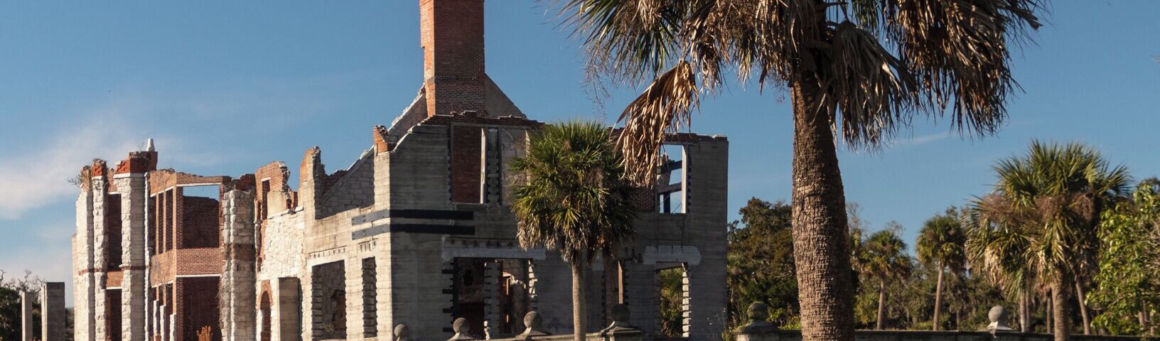 Dungeness on Cumberland Island, Georgia, is a ruined mansion that is part of a historic district that was the home of several families significant in American history. James Oglethorpe first built on Cumberland Island in 1736, building a hunting lodge that he named Dungeness. Oglethorpe named the place after Dungeness, in England. The next Dungeness was the legacy of Revolutionary War hero Nathanael Greene, who had acquired 11,000 acres of island land in exchange for a bad debt. His widow built a four-story tabby mansion in 1803, over a Timucuan shell mound. During the War of 1812 the island was occupied by the British, who used the house as a headquarters.
In 1818 Henry “Light-Horse Harry” Lee, a dashing cavalry commander during the Revolutionary War and father of Robert E. Lee, stayed at the house until his death on March 25, 1818, cared for by Greene's daughter Louisa, and was laid to rest in nearby cemetery with full military honors provided by an American fleet stationed at St. Marys, Georgia. The house was abandoned during the U.S. Civil War and burned in 1866.
In the 1880s the property was purchased by Thomas M. Carnegie, brother of Andrew Carnegie, who began to build a new mansion on the site. The 59-room Queen Anne style mansion and grounds were completed after Carnegie's death in 1886. His wife Lucy continued to live at Dungeness and built other estates for her children, including Greyfield for Margaret Carnegie, Plum Orchard for George Lauder Carnegie, and Stafford Plantation. By this time, the Carnegies owned 90% of the island.
The Carnegies moved out of Dungeness in 1925. In 1959 the Dungeness mansion was destroyed by fire, alleged to be arson. The ruins are today preserved by the National Park Service as part of Cumberland Island National Seashore. They were acquired by the Park Service in 1972.