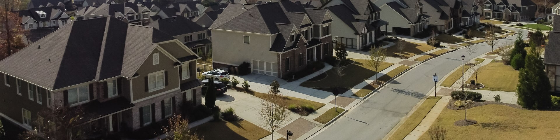 Aerial view upscale houses with side garage entry in new development subdivision sprawl leads to horizontal line under rare cloud formation suburbs Atlanta, Georgia, USA
