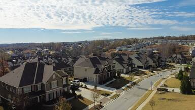 Aerial view upscale houses with side garage entry in new development subdivision sprawl leads to horizontal line under rare cloud formation suburbs Atlanta, Georgia, USA