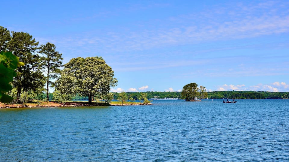 A calm lake with a small island and a boat in the distance.