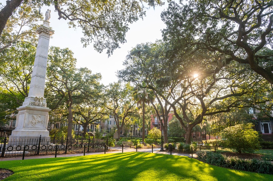 Scenic sunset view of public square in Savannah, Georgia with a monument dedicated in 1825 to Civil War General Casimir Pulaski, standing amongst tall oak trees