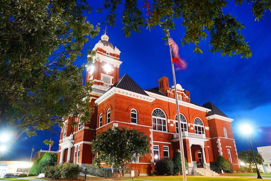 A large red brick building with a clock tower and arched windows at night.