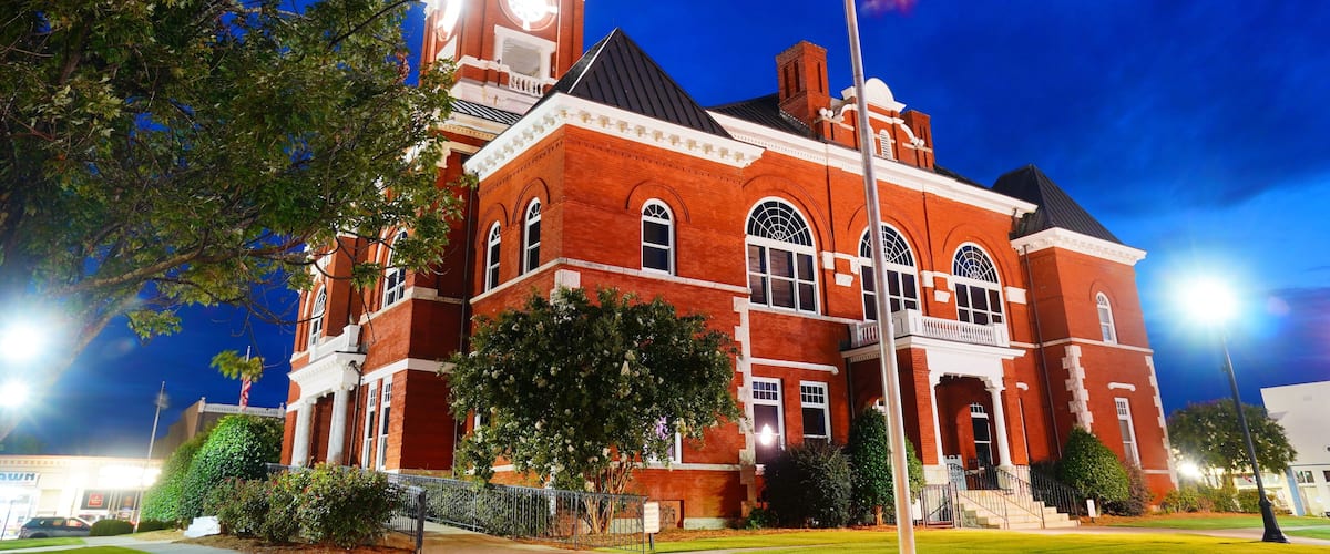 A large red brick building with a clock tower and arched windows at night.