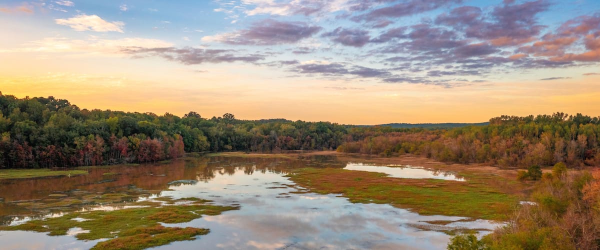A lake surrounded by trees with autumn foliage.