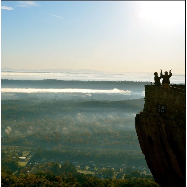 A cliff with a sign reading "Lovers Leap" overlooking a valley.