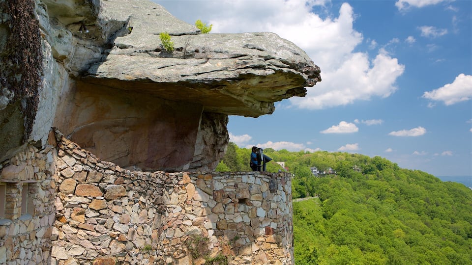 A rocky cliff with a person standing on a stone wall.