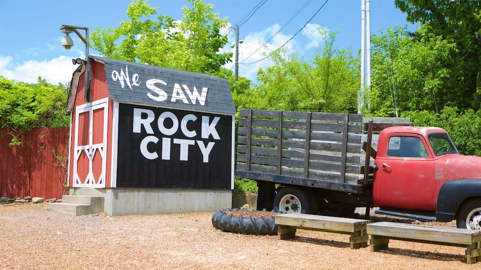 A red truck parked next to a building with a sign that reads "The Saw Rock City."