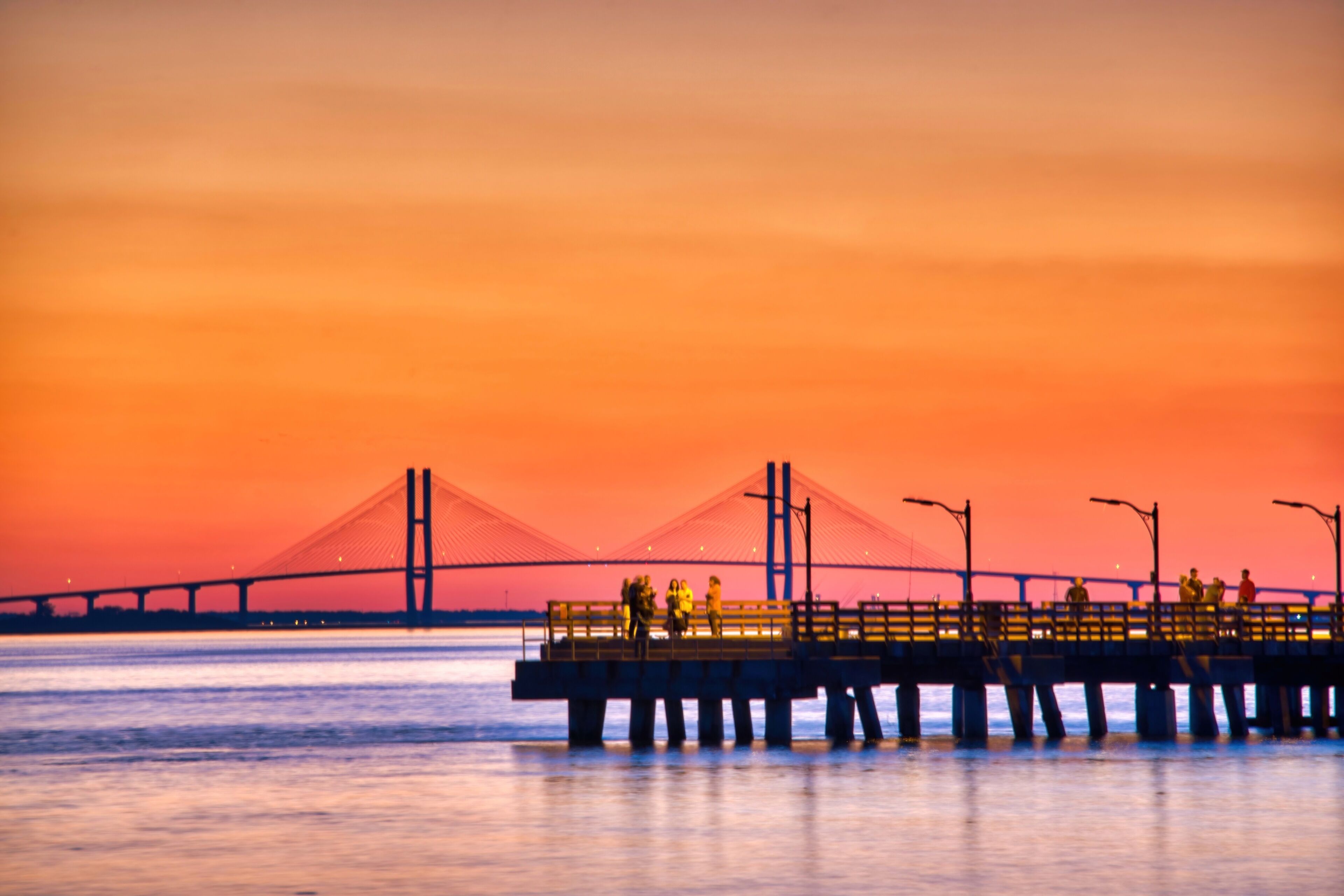 A bridge with a pedestrian walkway and a sunset in the background.