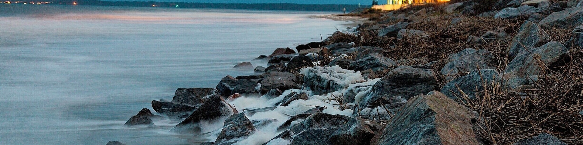 the entire time I was there I was clouded out of a sunset, So knowing that I wasn't going to get the sunset I went to see what high tide looks like on the island. It was brutal.
During high tide the entire beach disappears and water crashes up onto the sand dunes and barrier rocks. I captured this about 45 minutes after sunset. the color comes from the city lights just behind the buildings.
Image is about 1 minute long. I had to hold the tripod down when a wave would come in, always fun.