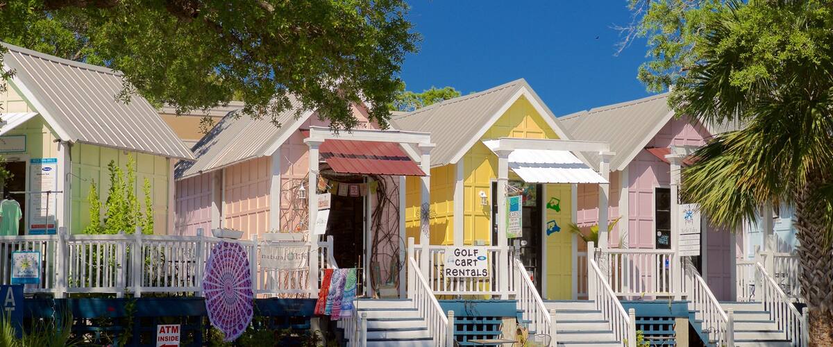 Casas de playa coloridas con un letrero de alquiler de carros de golf.