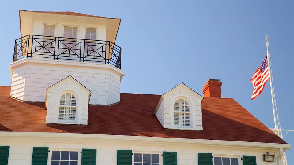 A white building with a red roof, green shutters, and an American flag.
