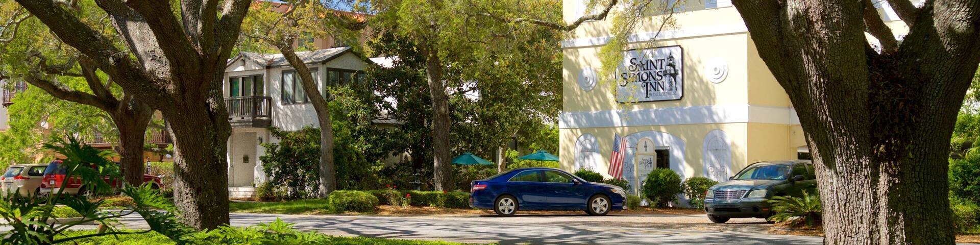 A street lined with trees and parked cars, with a building labeled "Saints Monks Inn" in the background.