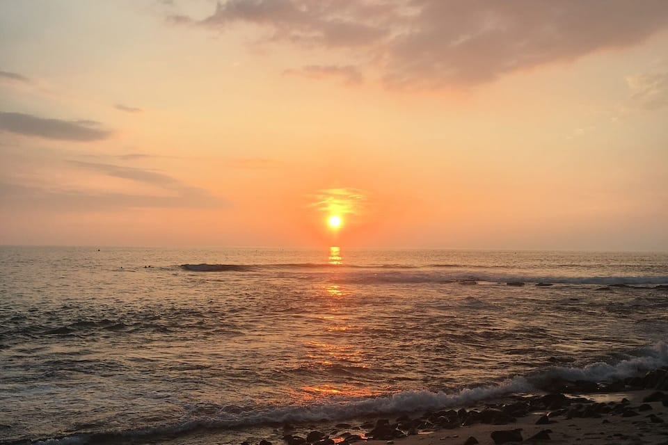 Un capvespre sobre una platja amb ones i petjades a la sorra.