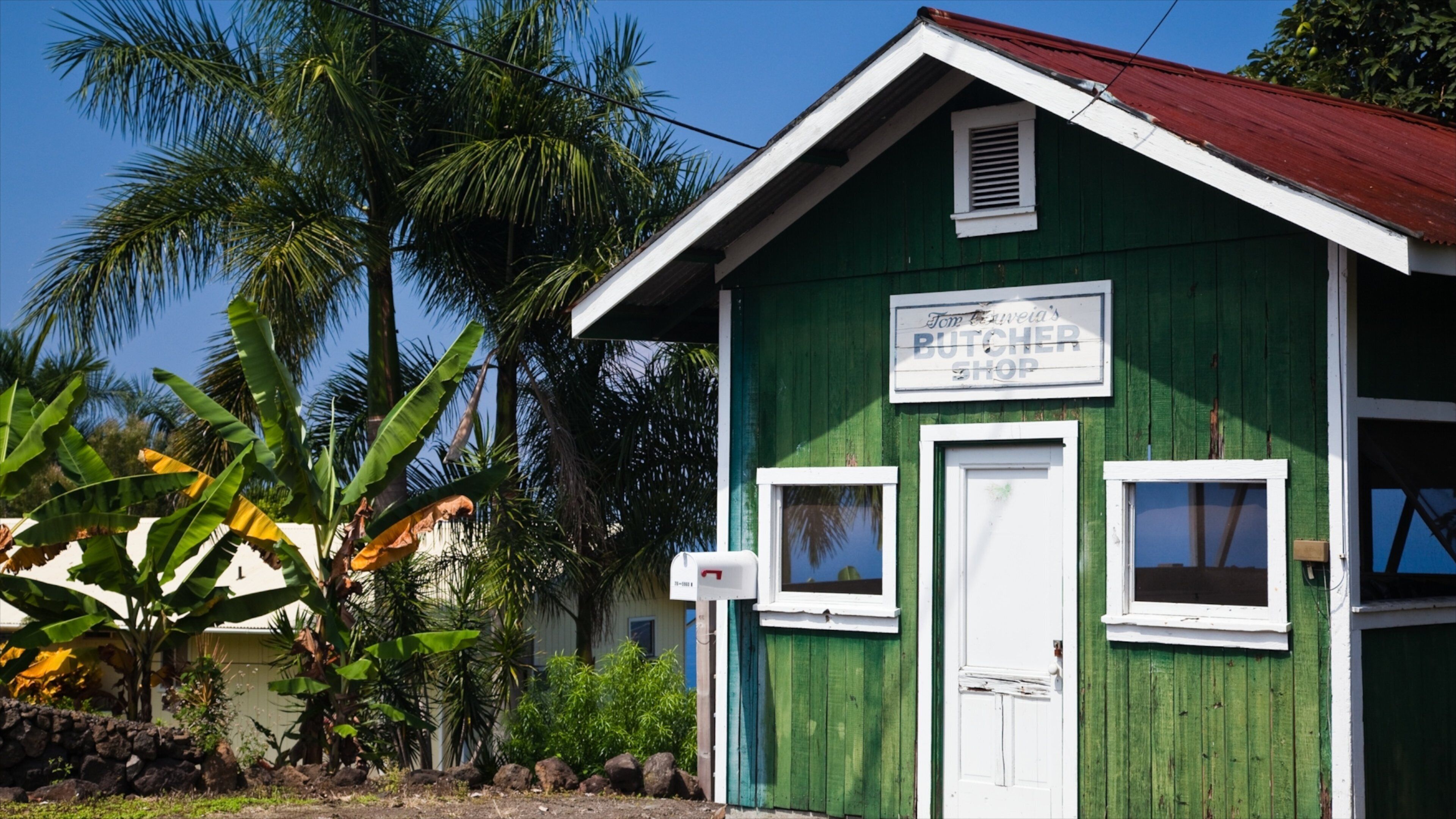 A green building with a sign that reads "Tom's Butcher Shop".