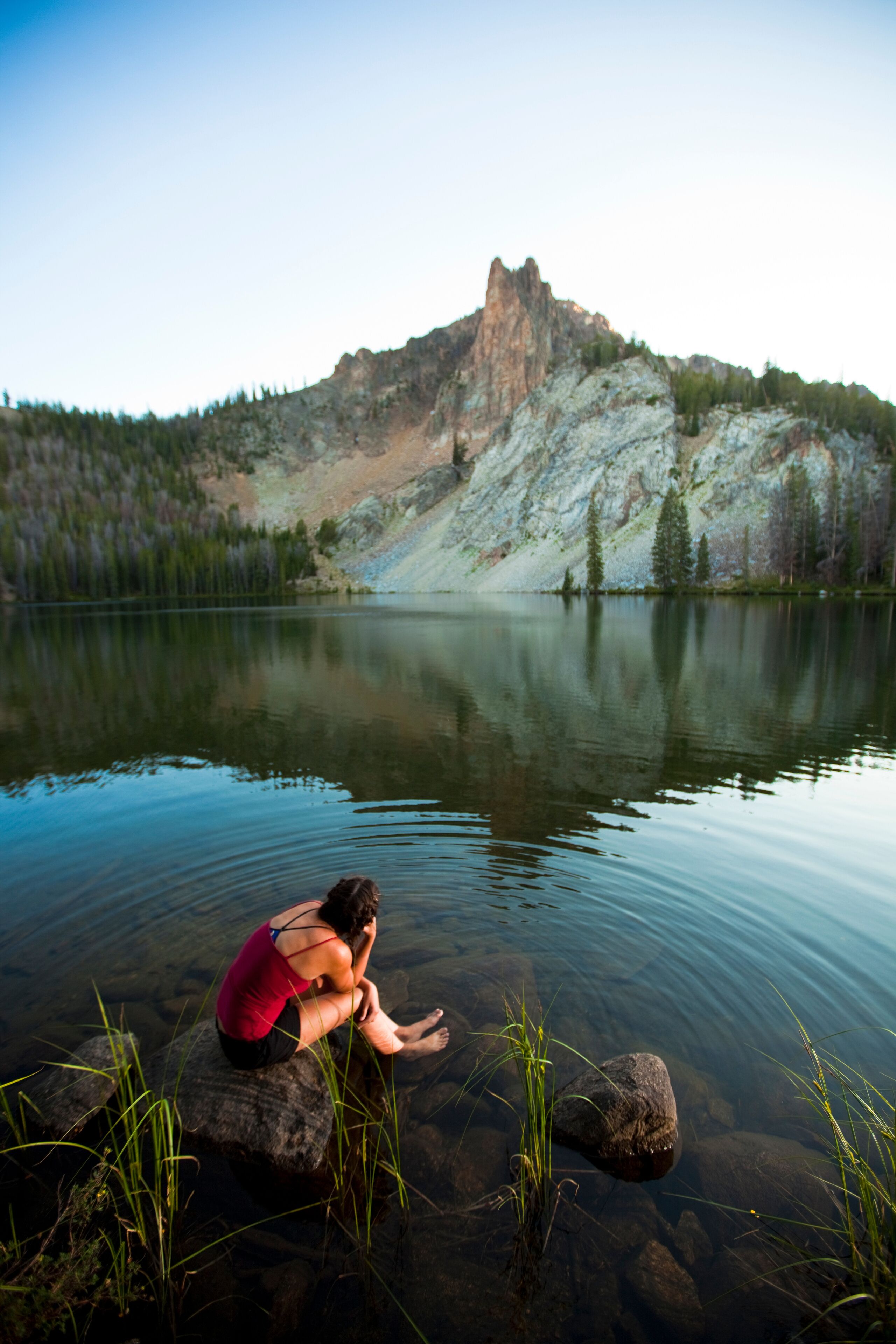 A woman soaks up the alpine bliss while sitting at Hatchett Lake afer a long day of backpacking in the White Cloud Mountains in Idaho.