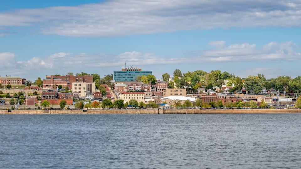 A riverside cityscape with historic buildings and a modern glass structure.
