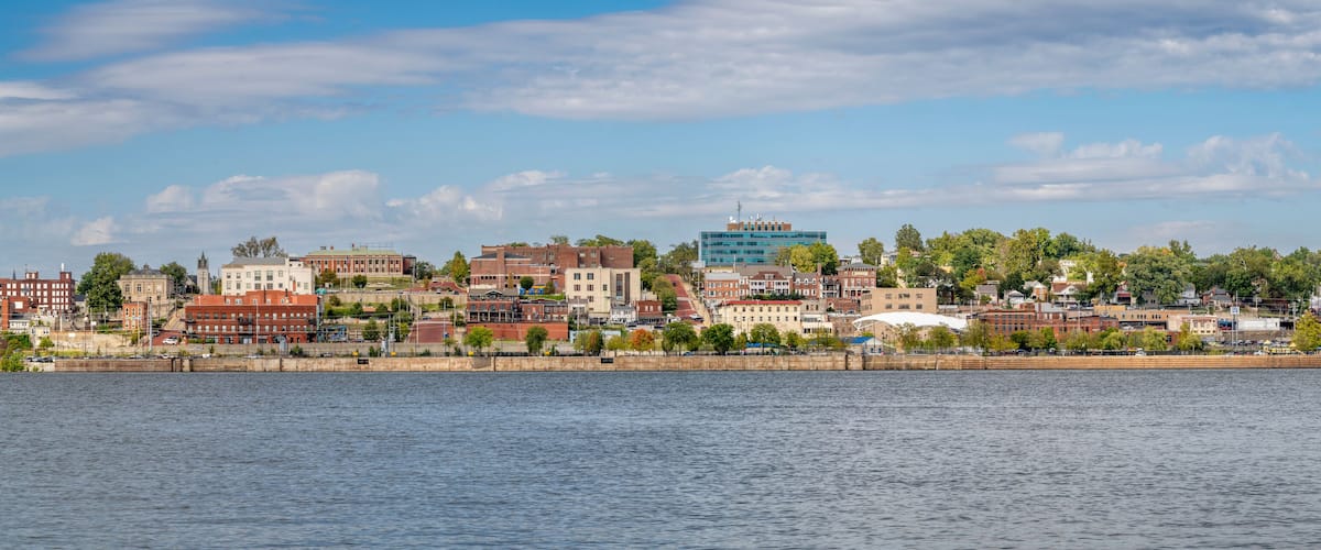 A riverside cityscape with historic buildings and a modern glass structure.