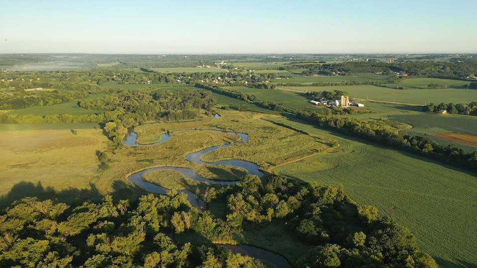 A river winding through a lush landscape with fields and scattered buildings.