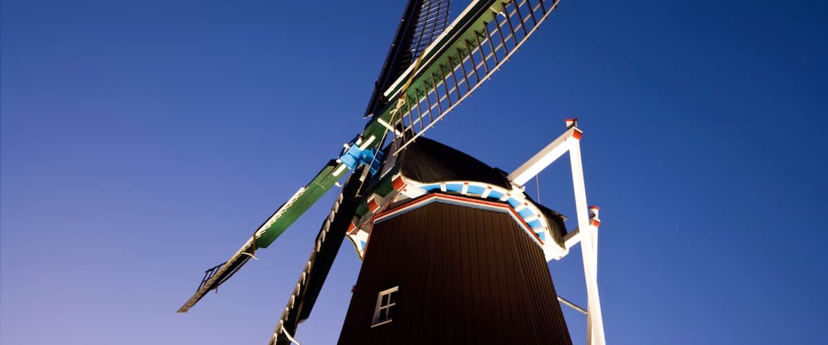 A windmill with a black body and white and red trim, set against a clear blue sky.