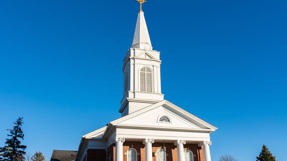 A church with a white steeple and a cross at the top.