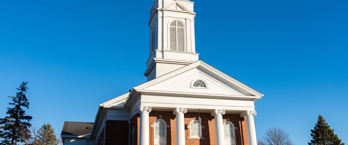 A church with a white steeple and a cross at the top.