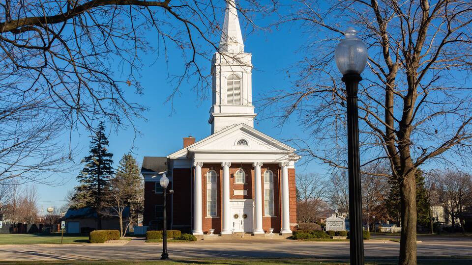 A church with a tall steeple and a brick facade.