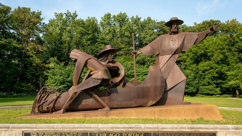 A large bronze statue of a Native American man in a canoe, with a plaque below.