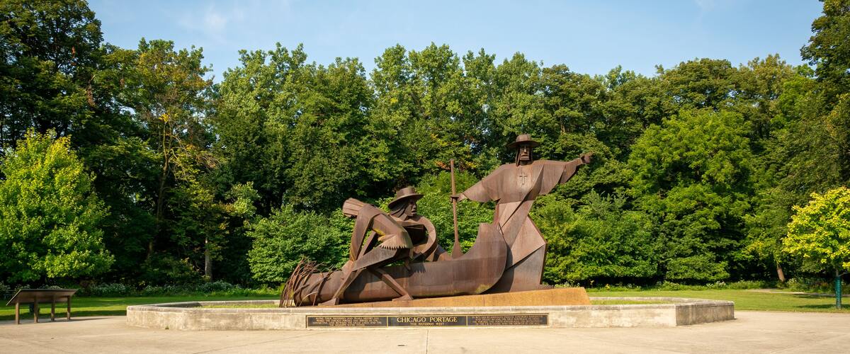 A bronze sculpture of a man in a hat and coat, with a shovel and a wheelbarrow, at the Chicago Portage National Historic Site.