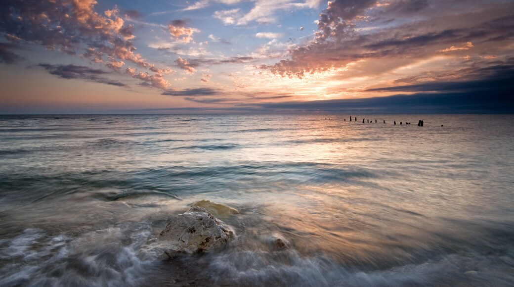 Summer sunrise over Lake Michigan with waves washing up on the shoreline.