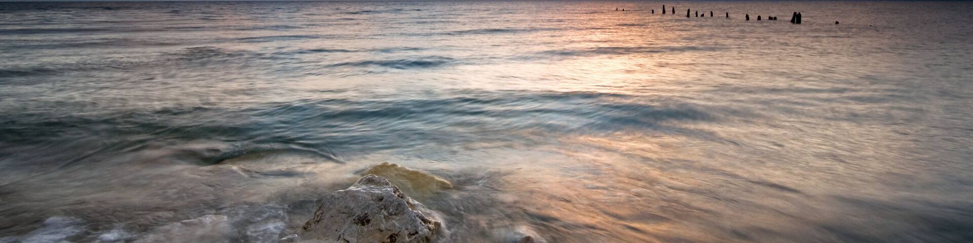 Summer sunrise over Lake Michigan with waves washing up on the shoreline.