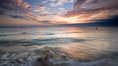 Summer sunrise over Lake Michigan with waves washing up on the shoreline.