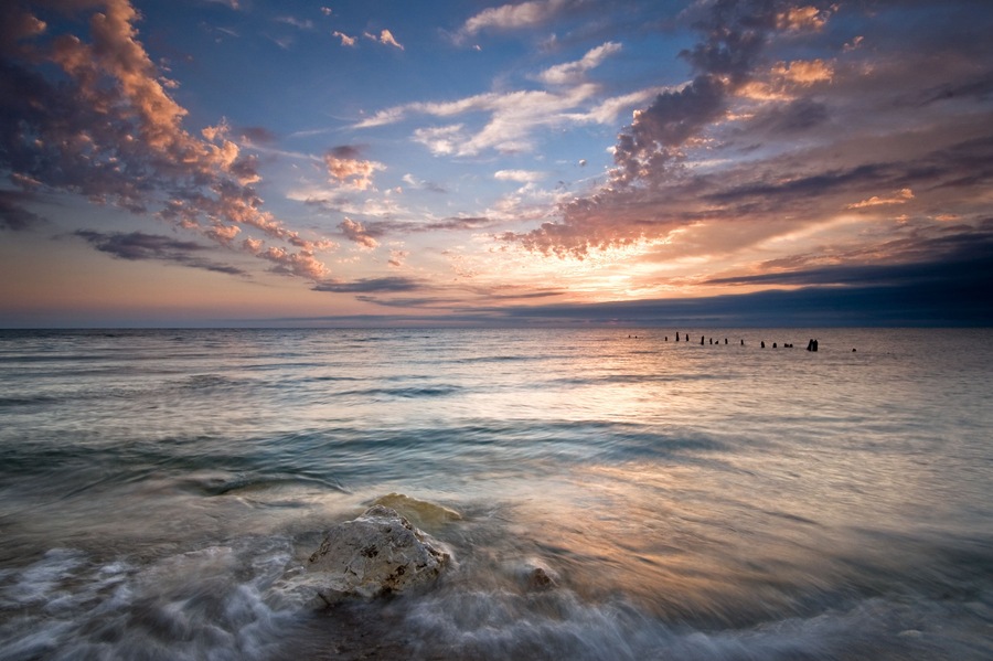Summer sunrise over Lake Michigan with waves washing up on the shoreline.