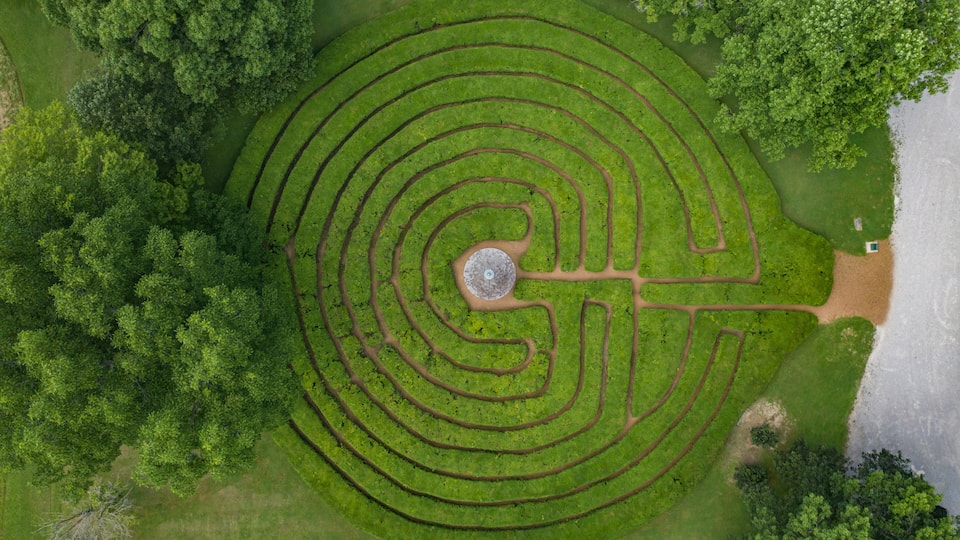 An aerial view of a labyrinth garden with concentric paths and a central stone.