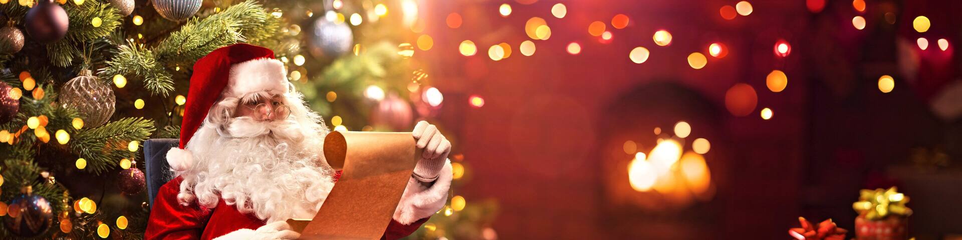 Santa Claus Sitting at His Room at Home Near Christmas Tree and Reading Christmas Letter or Wish List