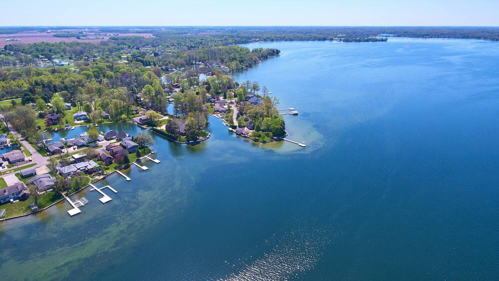 An aerial view of a lakeside community with residential houses, docks, and boats.