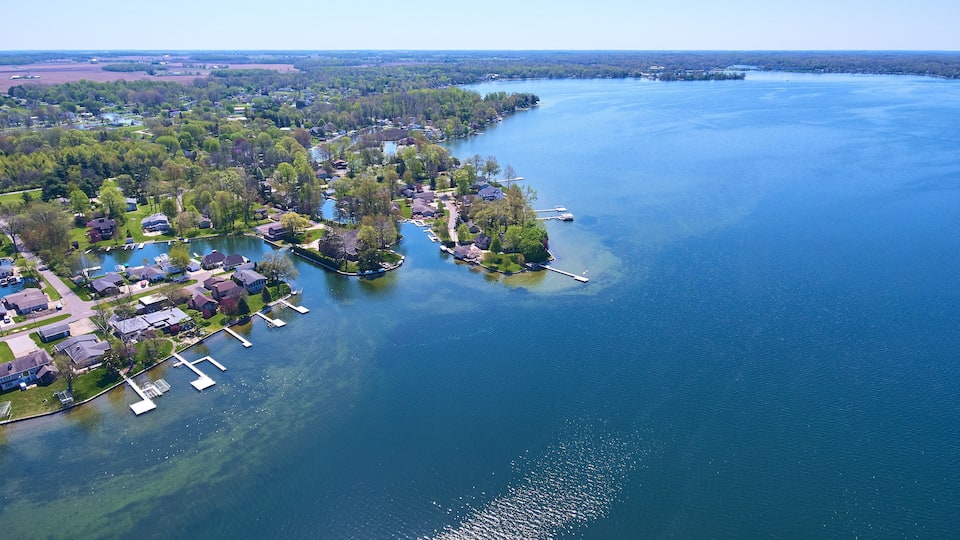 An aerial view of a lakeside community with residential houses, docks, and boats.