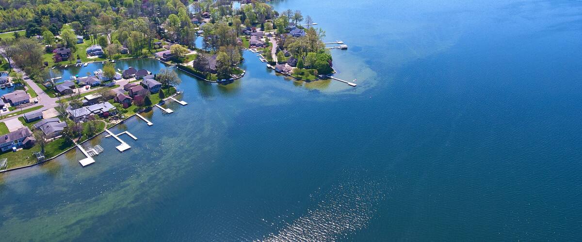 An aerial view of a lakeside community with residential houses, docks, and boats.