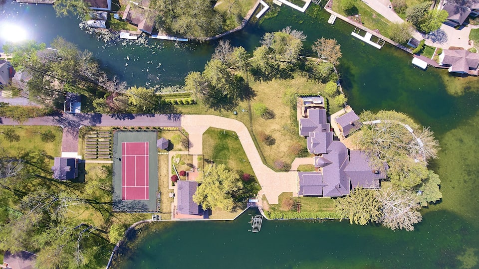 An aerial view of a lakeside community with houses, a tennis court, and a dock.